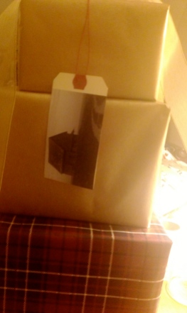 Stack of presents wrapped in plain brown kraft paper and tartan, with DIY photograph luggage tag
